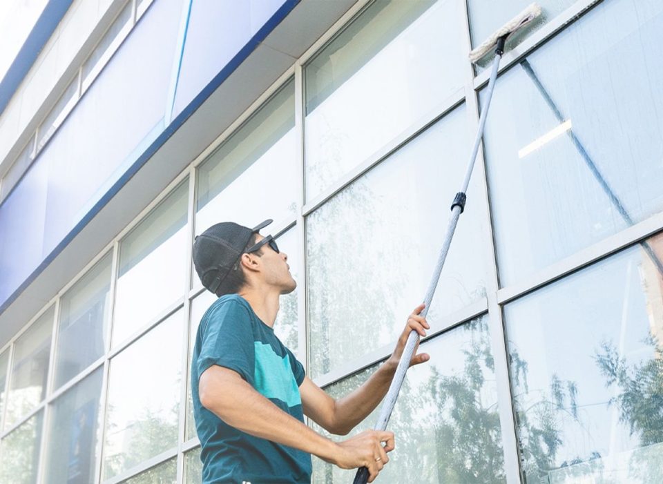 A man is diligently cleaning the windows of a tall building, ensuring a clear view for occupants and passersby.