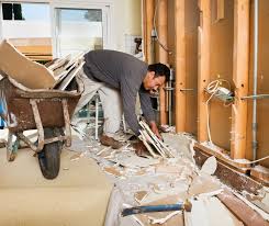 Worker cleaning up construction debris inside a partially renovated home.